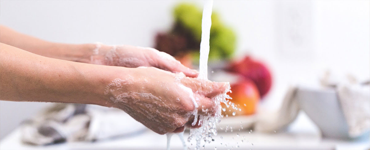 A pair of hands rinsing lingerie under a tap