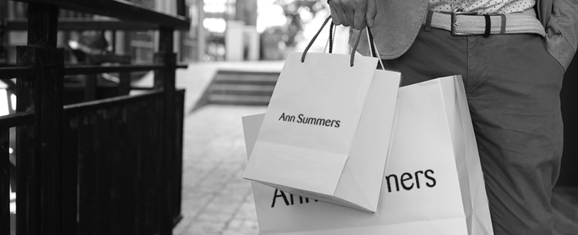 Busy street with a man holding Ann Summers Shopping bag.