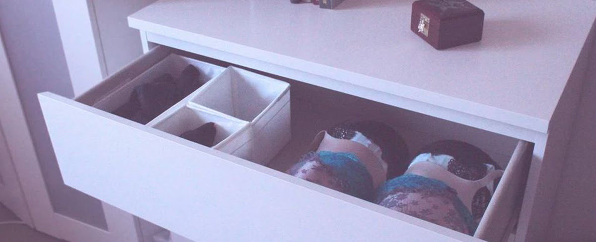 An open lingerie drawer with bras neatly placed in a row