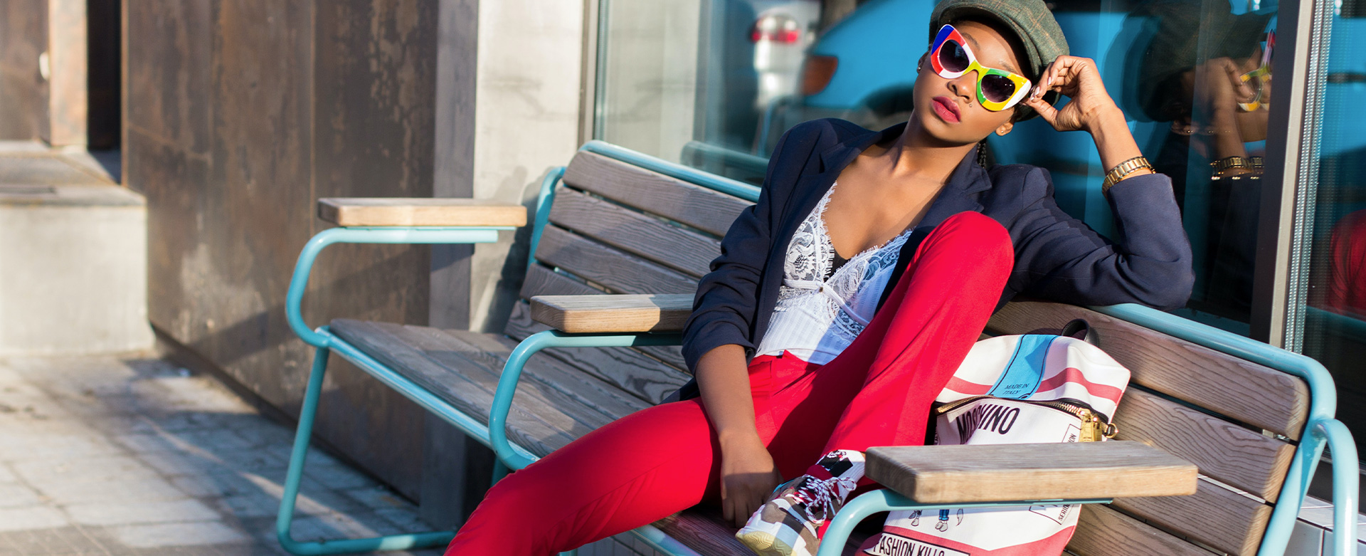 Woman in a white corset paired with high waisted flared red trousers layered with a navy blazer.